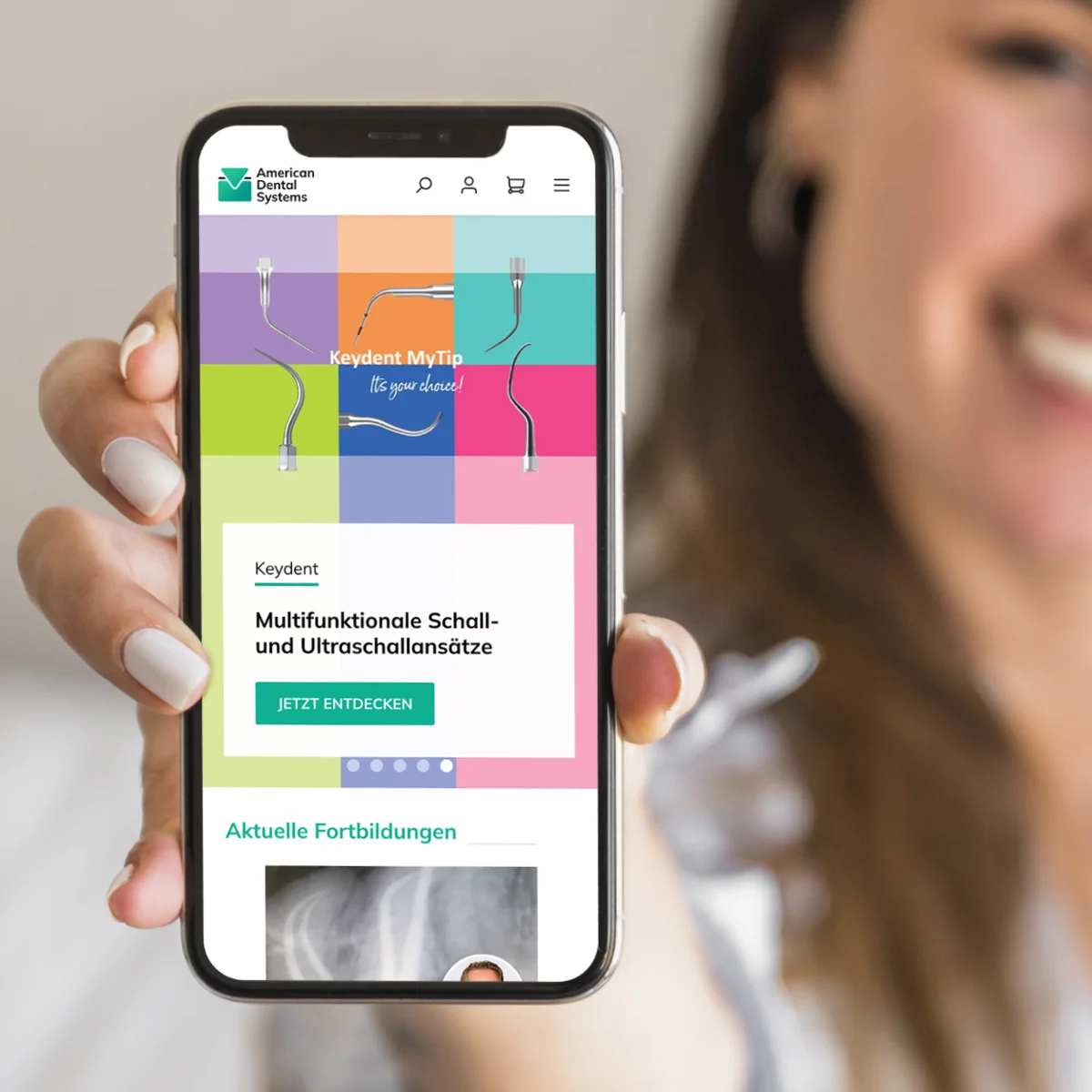 Mobilny interfejs e-commerce American Dental Systems na smartfonie trzymanym przez kobietę, prezentujący profesjonalne instrumenty dentystyczne