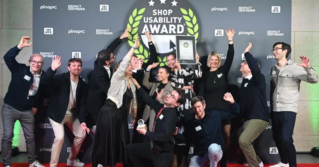 A group of people celebrating on a red carpet with an award, under a "Shop Usability Award" banner.