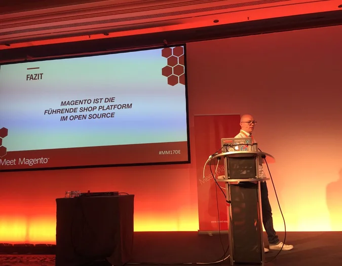 Prelegent na wydarzeniu Meet Magento prezentujący slajd zatytułowany „FAZIT” o Magento jako wiodącej platformie sklepowej open source
