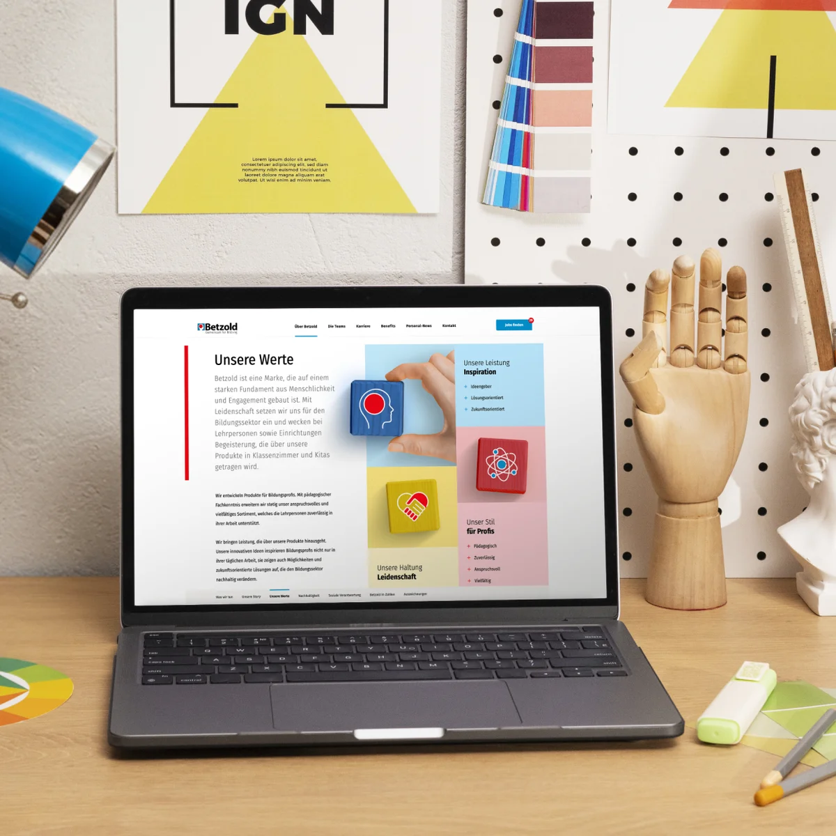Podgląd strony e-commerce Betzold na laptopie prezentujący stronę firmową „Unsere Werte” (Nasze wartości) w kreatywnym otoczeniu biurowym