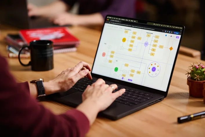Projektant pracujący nad architekturą informacji i nawigacją na laptopie