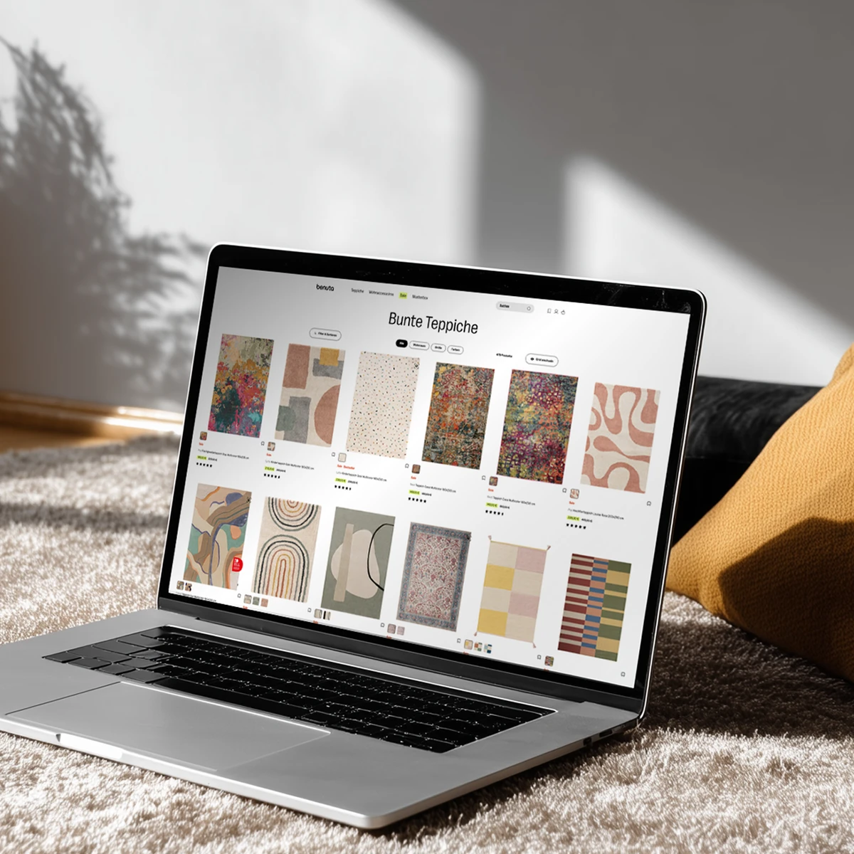 Podgląd strony e-commerce Benuta na laptopie prezentujący kolekcję kolorowych dywanów w nowoczesnej aranżacji salonu