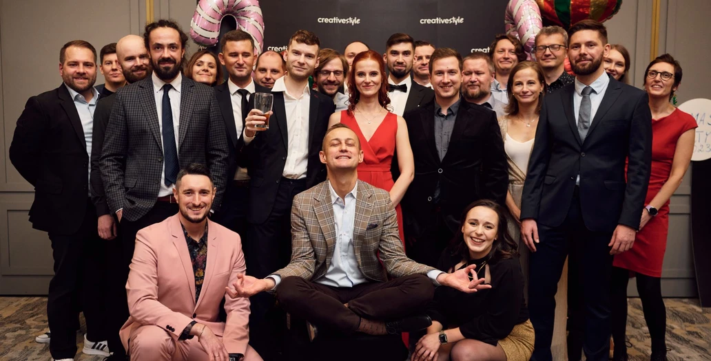 Duża grupa członków zespołu pozuje na przyjęciu bożonarodzeniowym creative style z świątecznymi dekoracjami