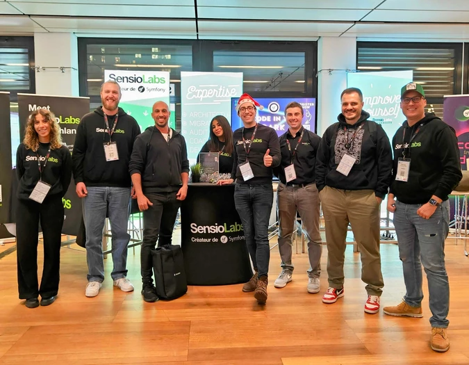 Członkowie zespołu SensioLabs pozują na stoisku eventowym z banerami Expertise i Symfony